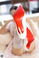 A woman laying on a bed with a pair of red and white shoes.