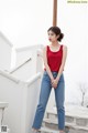 a woman in a red top and jeans standing on some steps