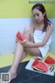 A woman sitting on the floor eating a slice of watermelon.