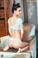 A woman in a white lingerie sitting on a chair.