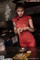 A woman in a red dress preparing food in a kitchen.