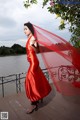 A woman in a red dress standing on a bridge.