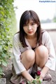 A woman sitting on the ground with a rose in her hand.