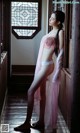 A woman in a pink lingerie leaning against a window.