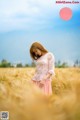 A woman standing in a field of wheat.