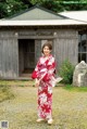 A woman in a red and white kimono standing in front of a building.