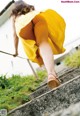 A woman in a yellow dress is walking up some steps.