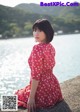 A woman in a red dress sitting by the water.