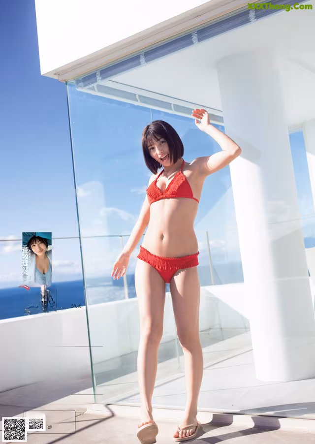 A woman in a red bikini standing on a balcony.