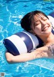 A woman laying on an inflatable pillow in a swimming pool.