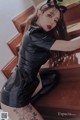 A woman in a black latex outfit sitting on a staircase.