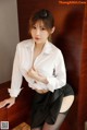 A woman in a white shirt and black skirt posing for a picture.