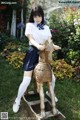 A woman in a school uniform riding a wooden horse.