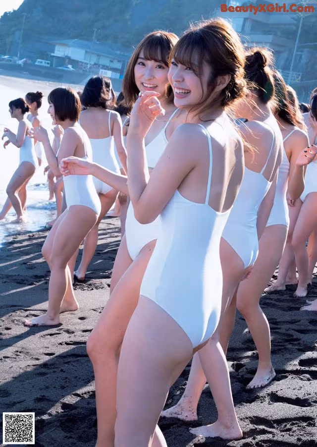 A group of women in white bathing suits standing on a beach.
