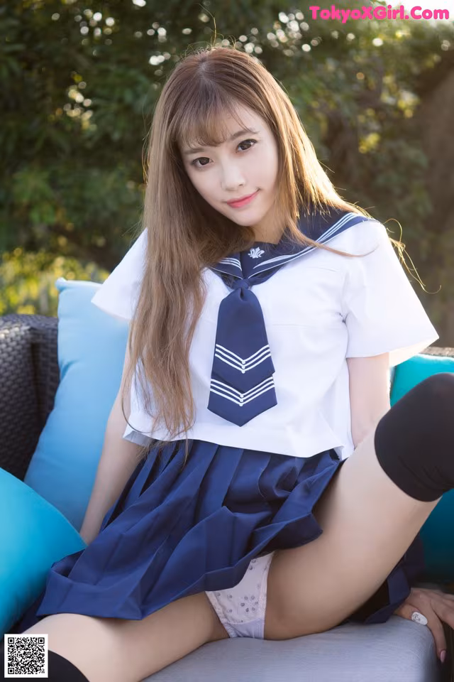 A woman in a school uniform sitting on a couch.