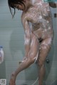 A naked woman is taking a shower in the bathroom.