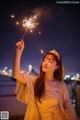 A woman in a yellow dress holding a sparkler.