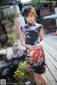 A woman in a black dress standing on a wooden deck.